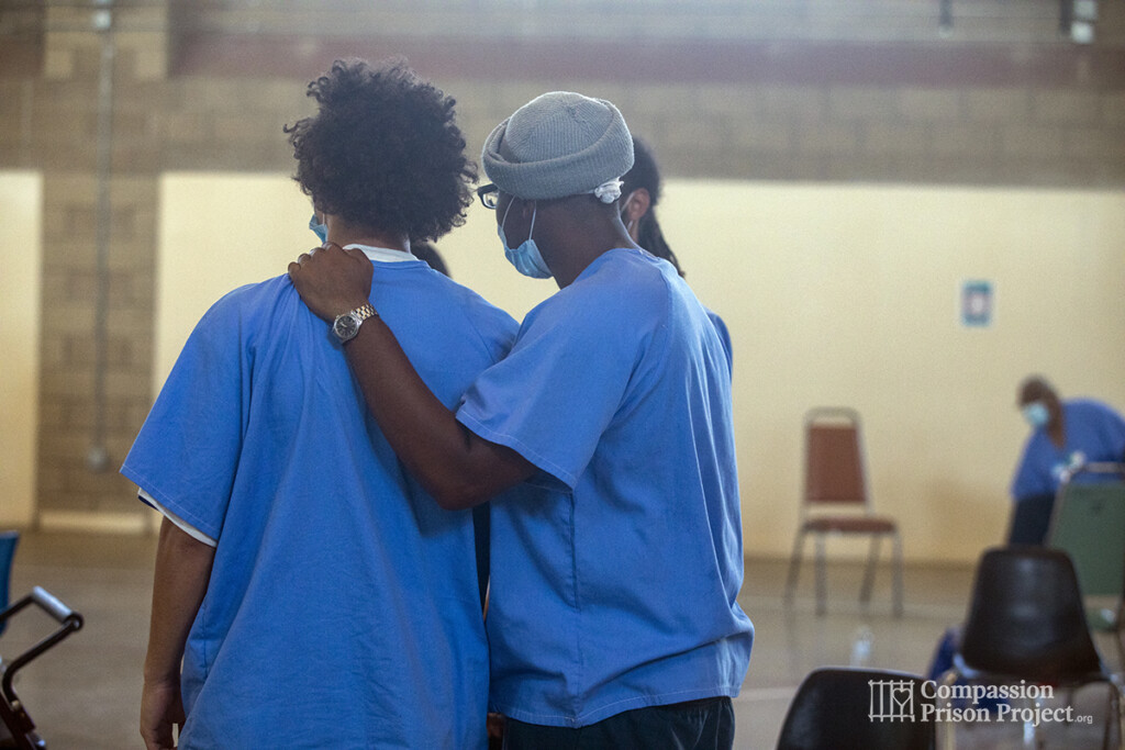 Two men in prison standing with arm on shoulder